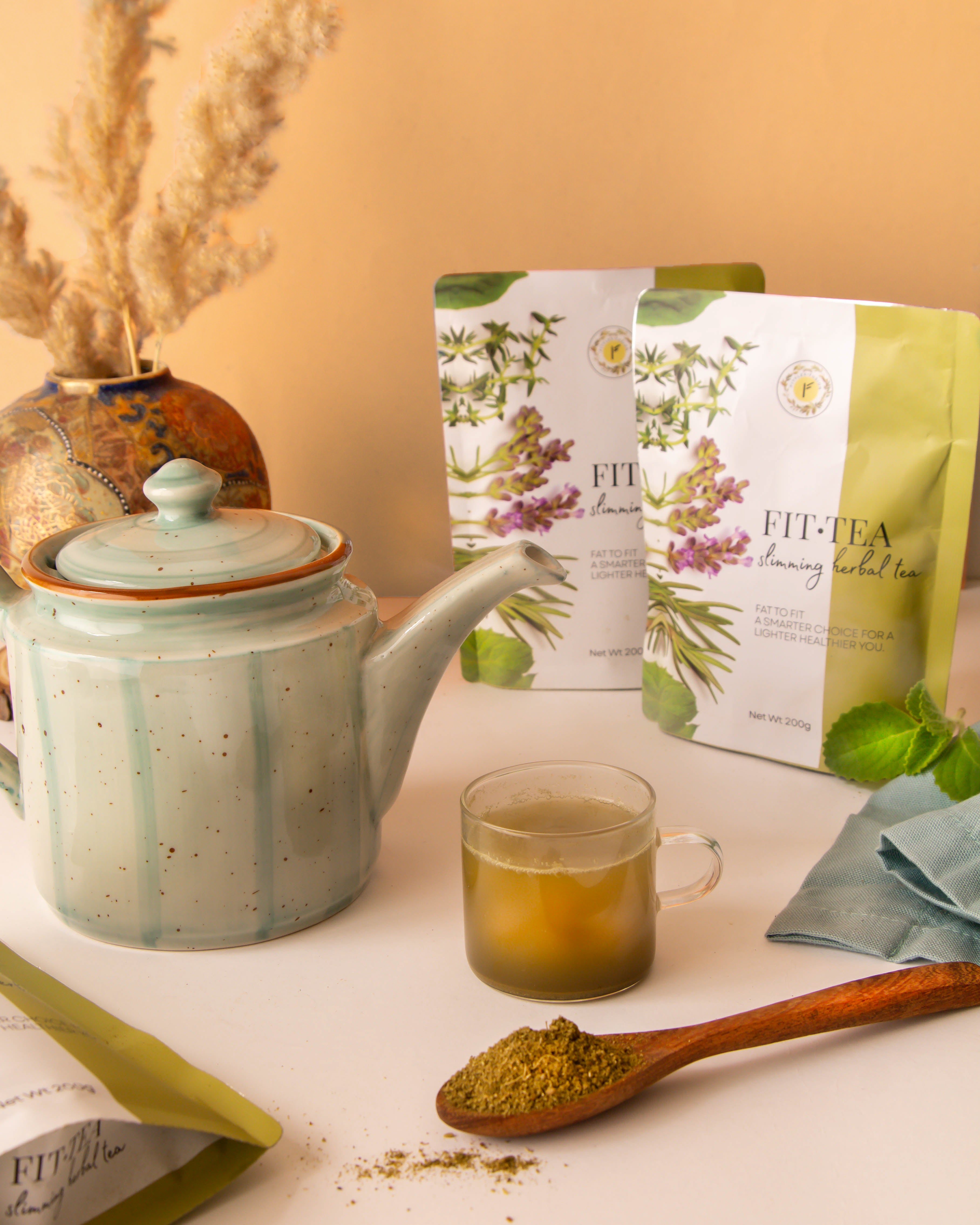 Fit Tea Slimming Herbal Tea served hot in a teapot and cup alongside product pouches